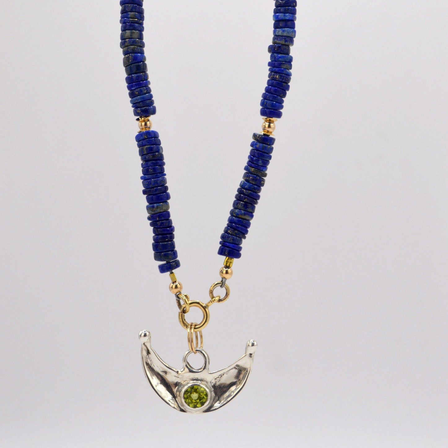 Necklace with blue beads and a silver crescent moon pendant on a white background