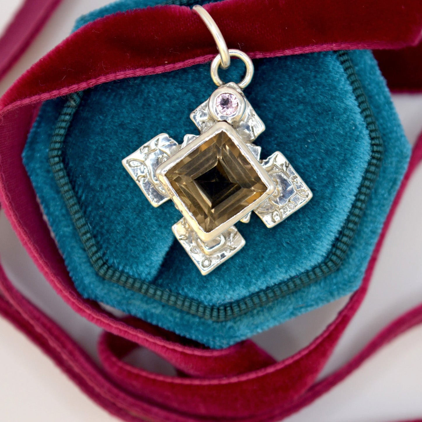 Decorative brooch with gemstone on a teal fabric background