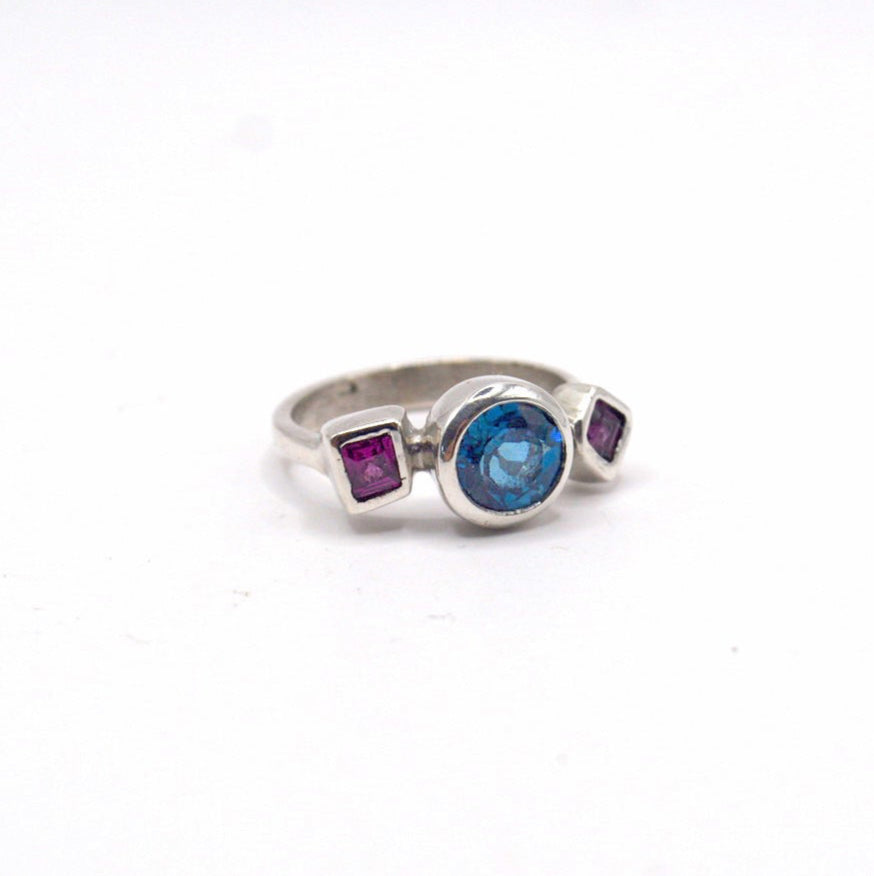 Silver ring with colored gemstones on a white background