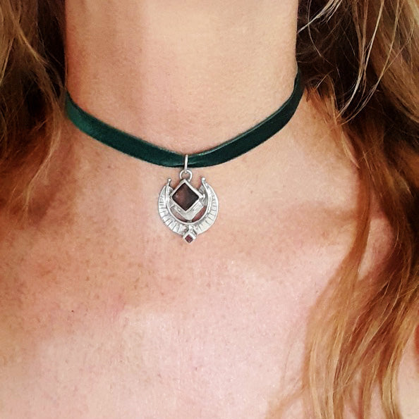 Green velvet choker with a silver pendant on a person's neck