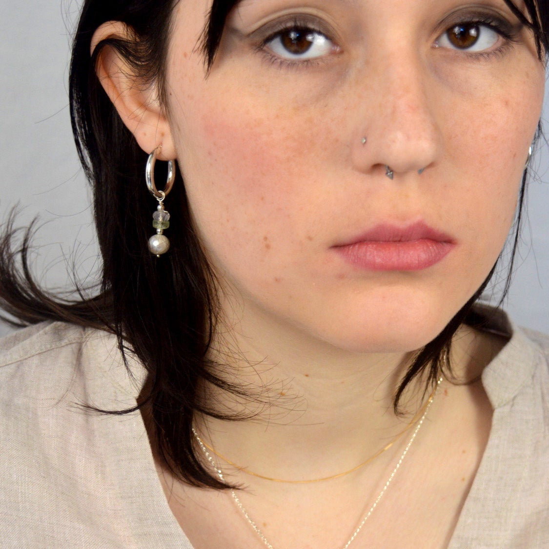Woman wearing a light-colored top against a plain background