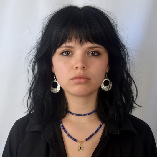 Woman wearing black shirt and jewelry against a white background
