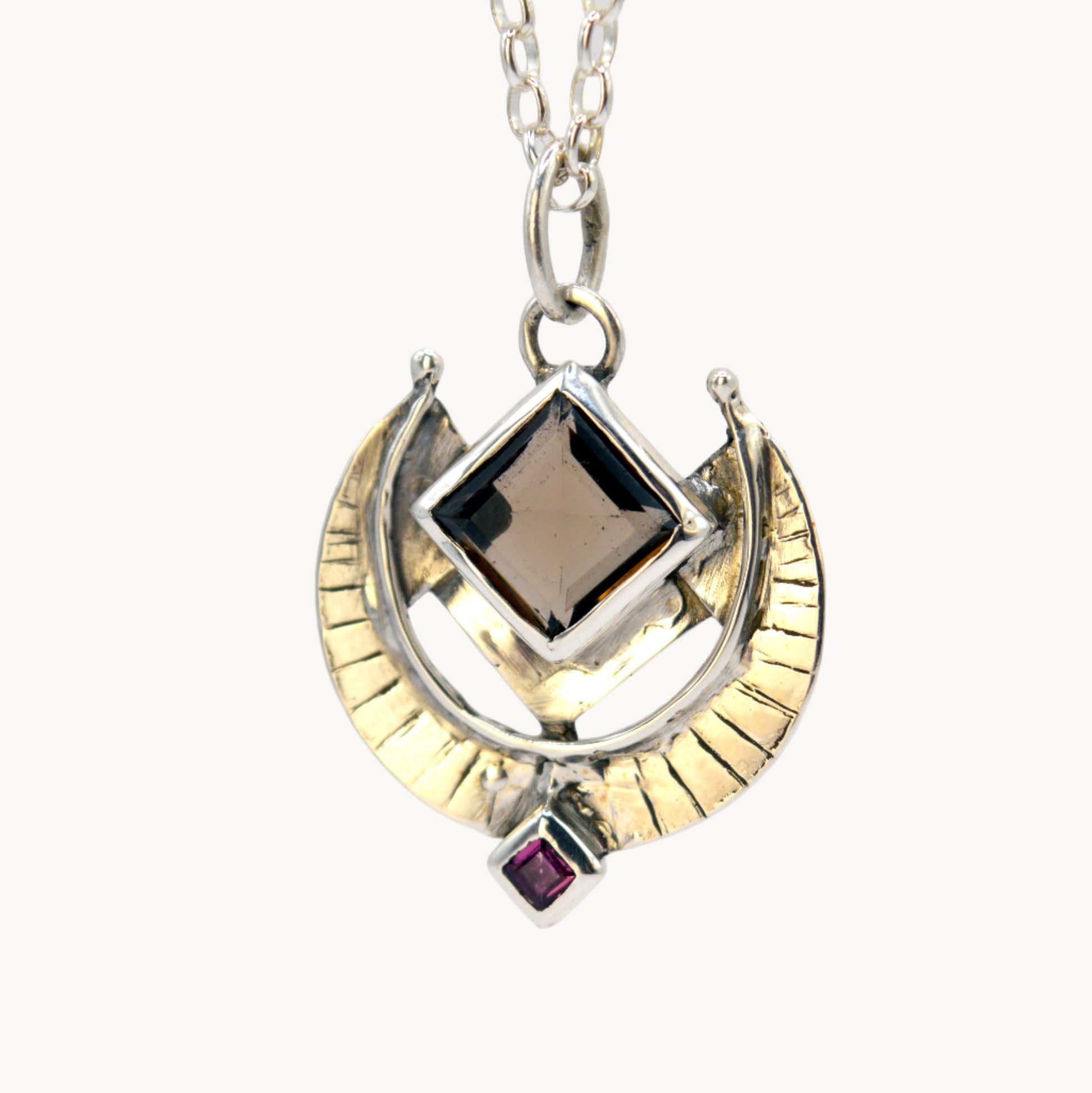 Necklace with a gold and silver pendant on a light gray background