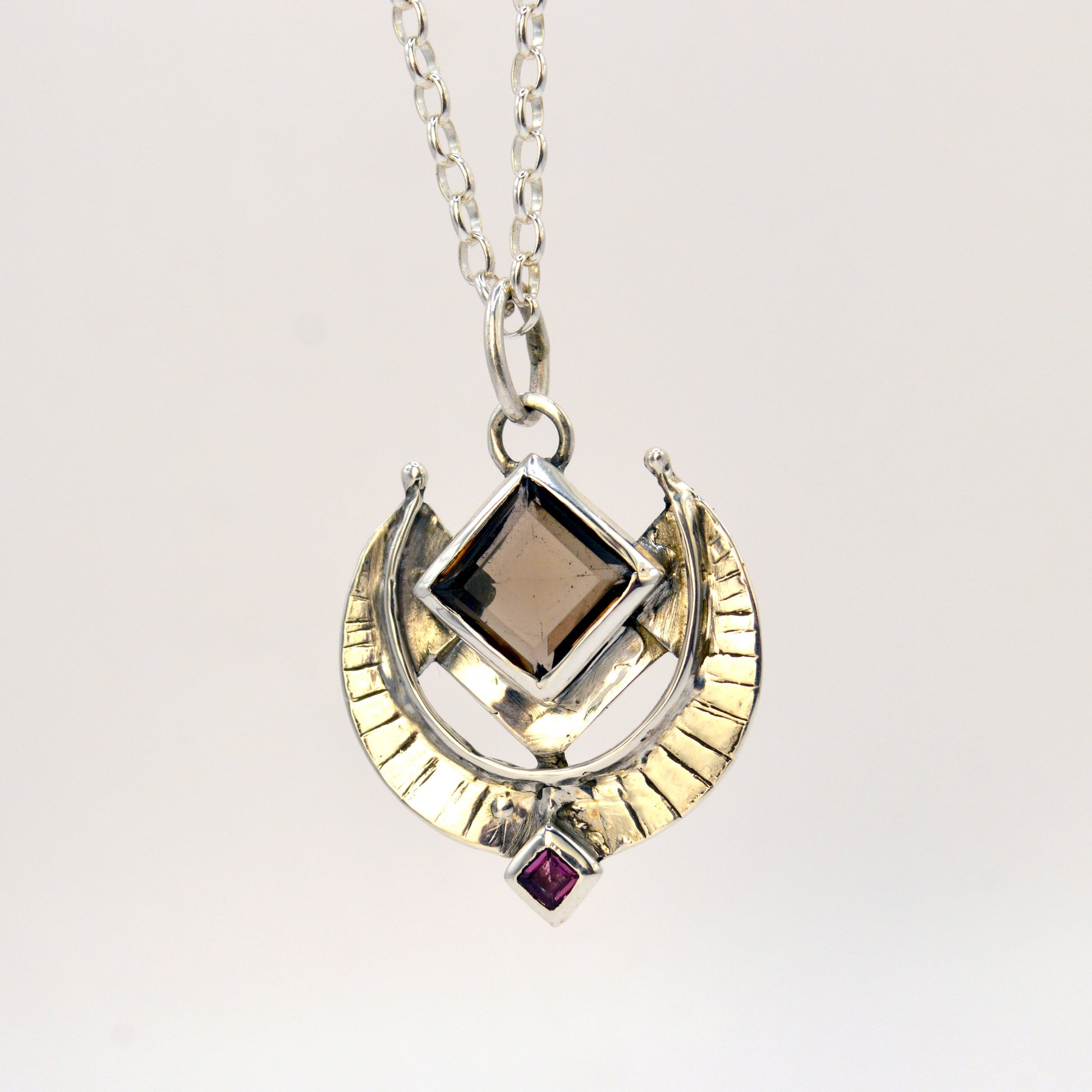 Necklace with a pendant featuring a square gemstone and a circular design on a white background
