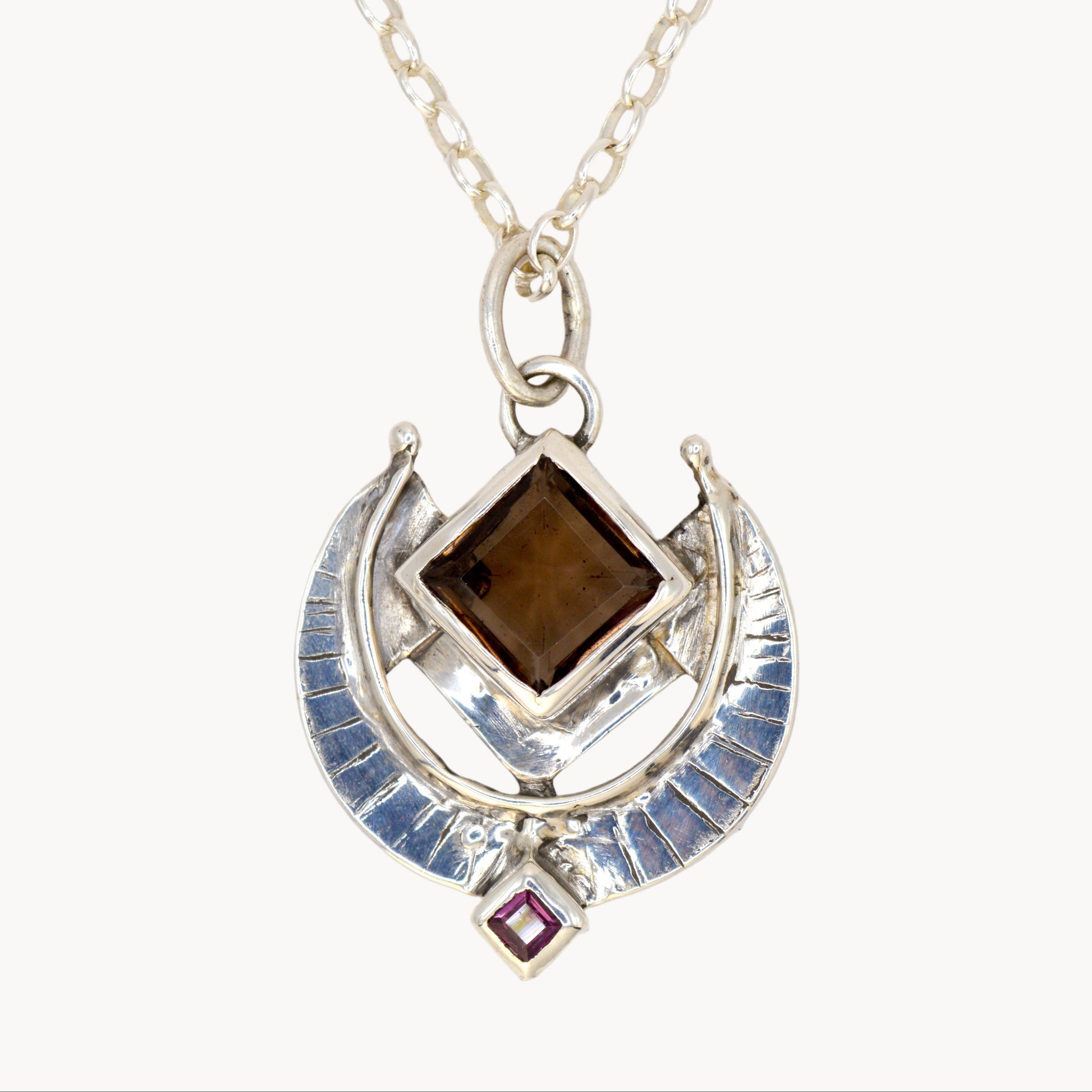 Silver pendant necklace with brown gemstone on a white background