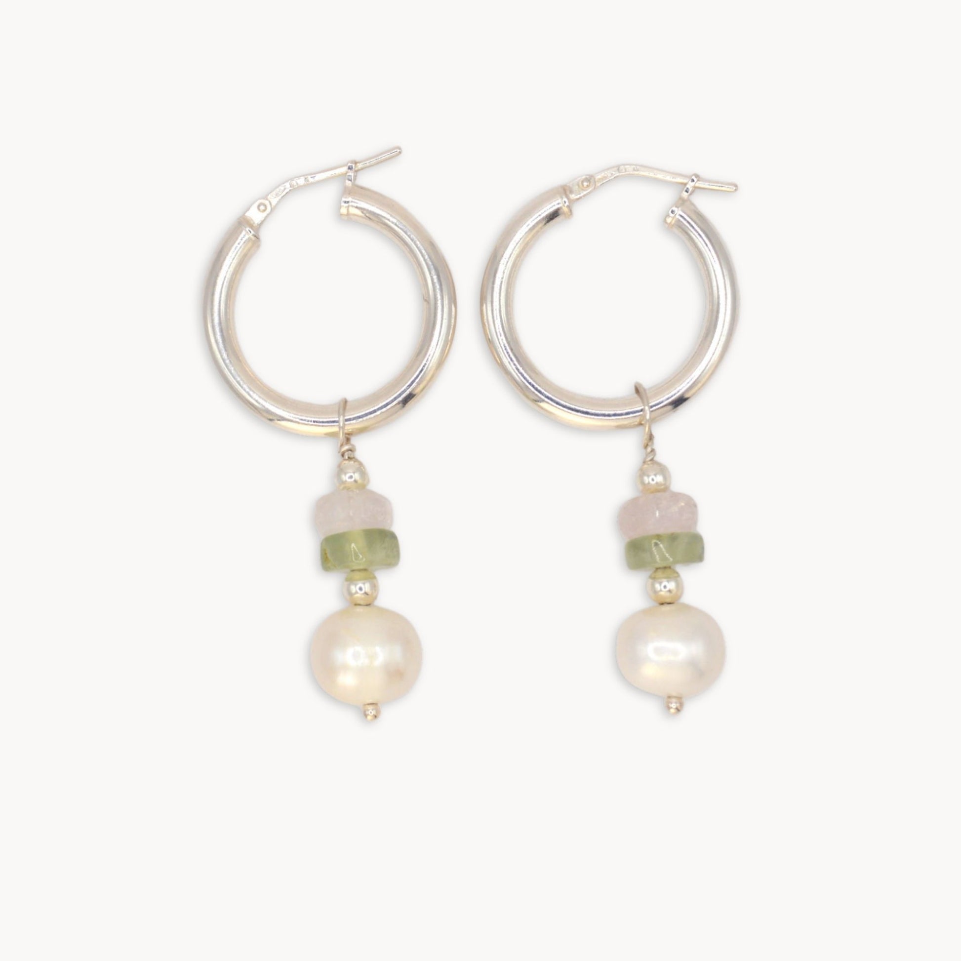 Silver hoop earrings with pearl and green bead drops on a white background