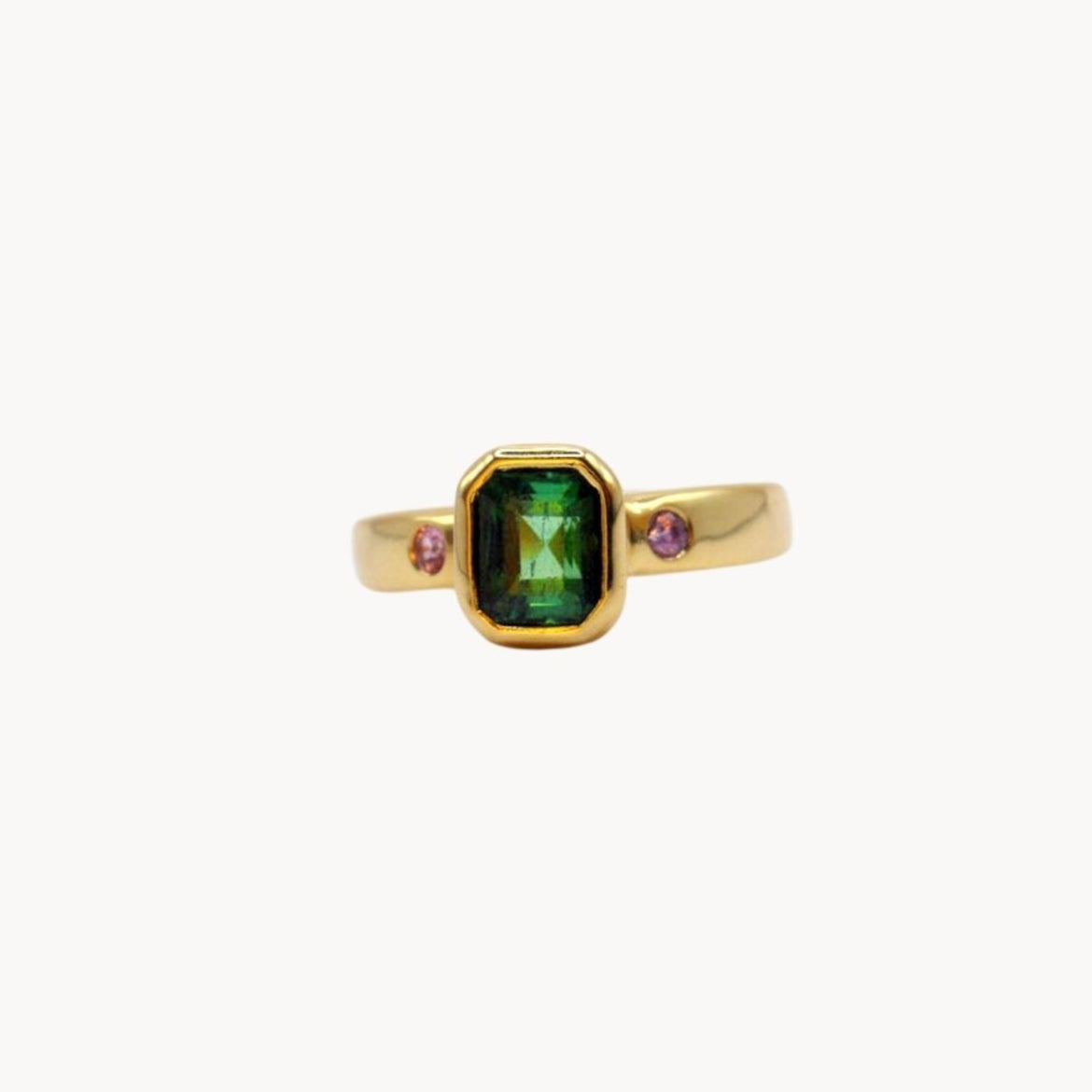 Gold ring with a green gemstone on a white background