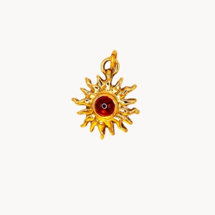 Gold pendant with a red gemstone on a white background
