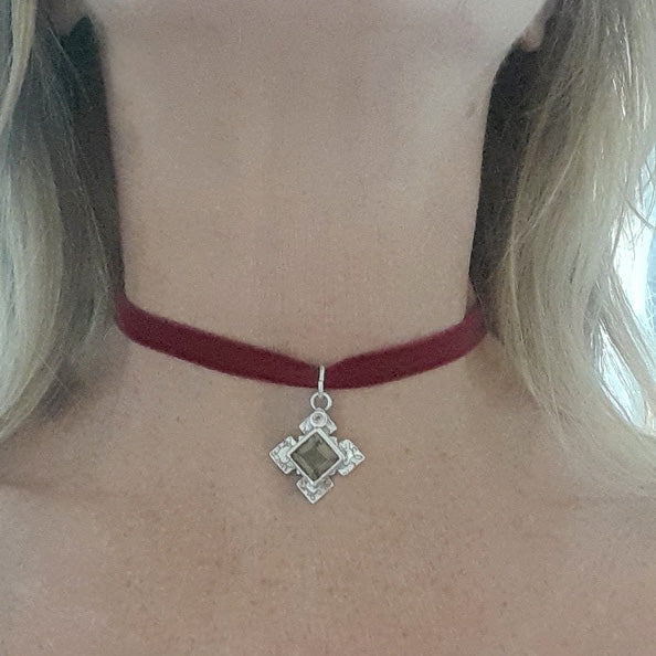 Red choker necklace with a silver pendant on a person's neck