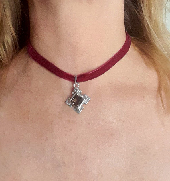 Red choker necklace with a silver pendant worn by a person