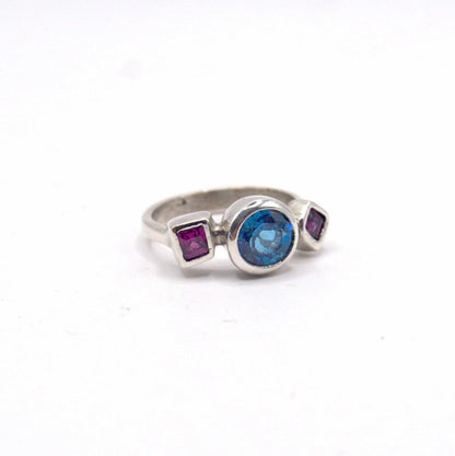 Silver ring with colored gemstones on a white background