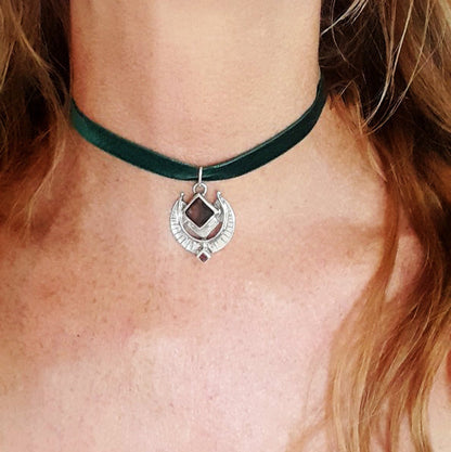 Green velvet choker with a silver pendant on a person's neck