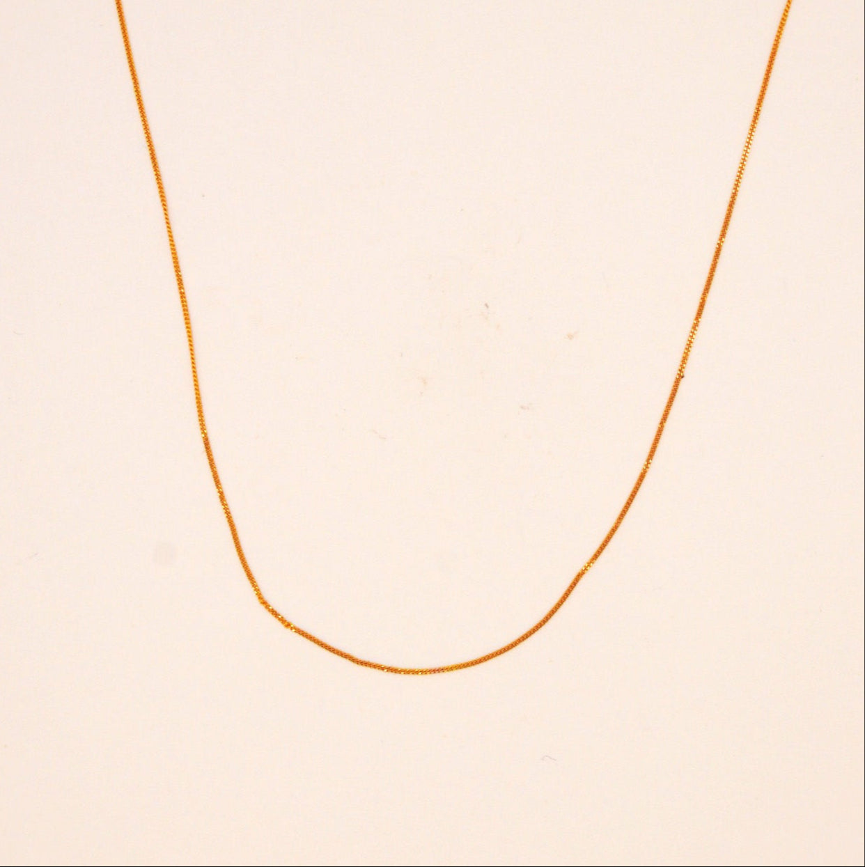 Gold necklace on a beige background
