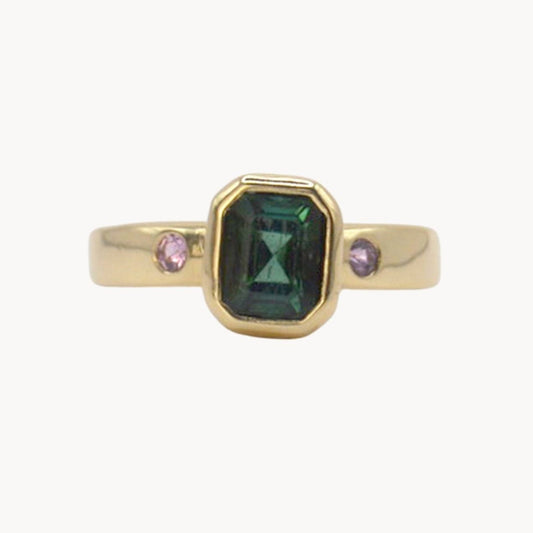 Gold ring with a green gemstone and pink stones on a white background
