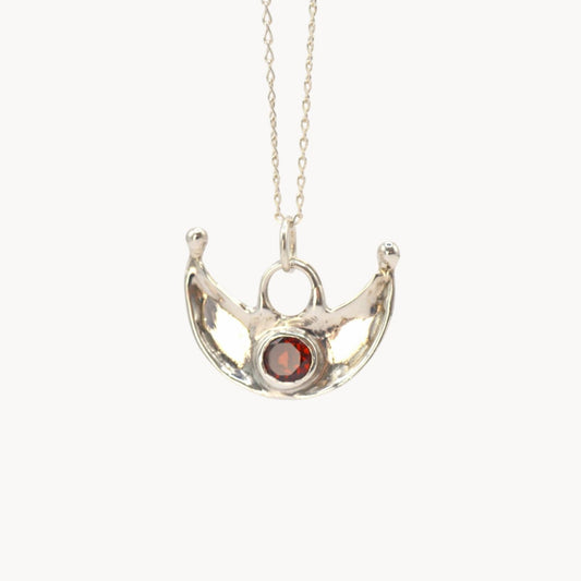 Silver necklace with a pendant featuring a red gemstone on a white background
