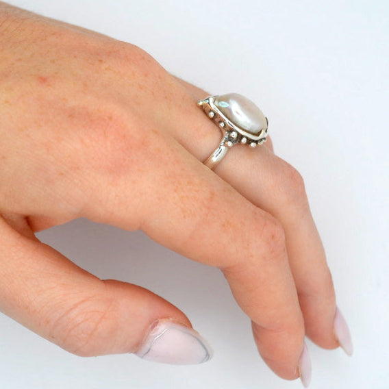 Hand wearing a silver ring on a white background