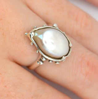 Hand wearing a ring with a large gemstone on a white background