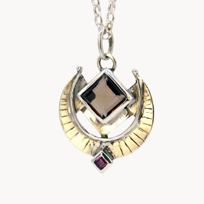 Necklace with a gold and silver pendant on a light gray background