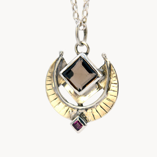 Necklace with a gold and silver pendant on a light gray background