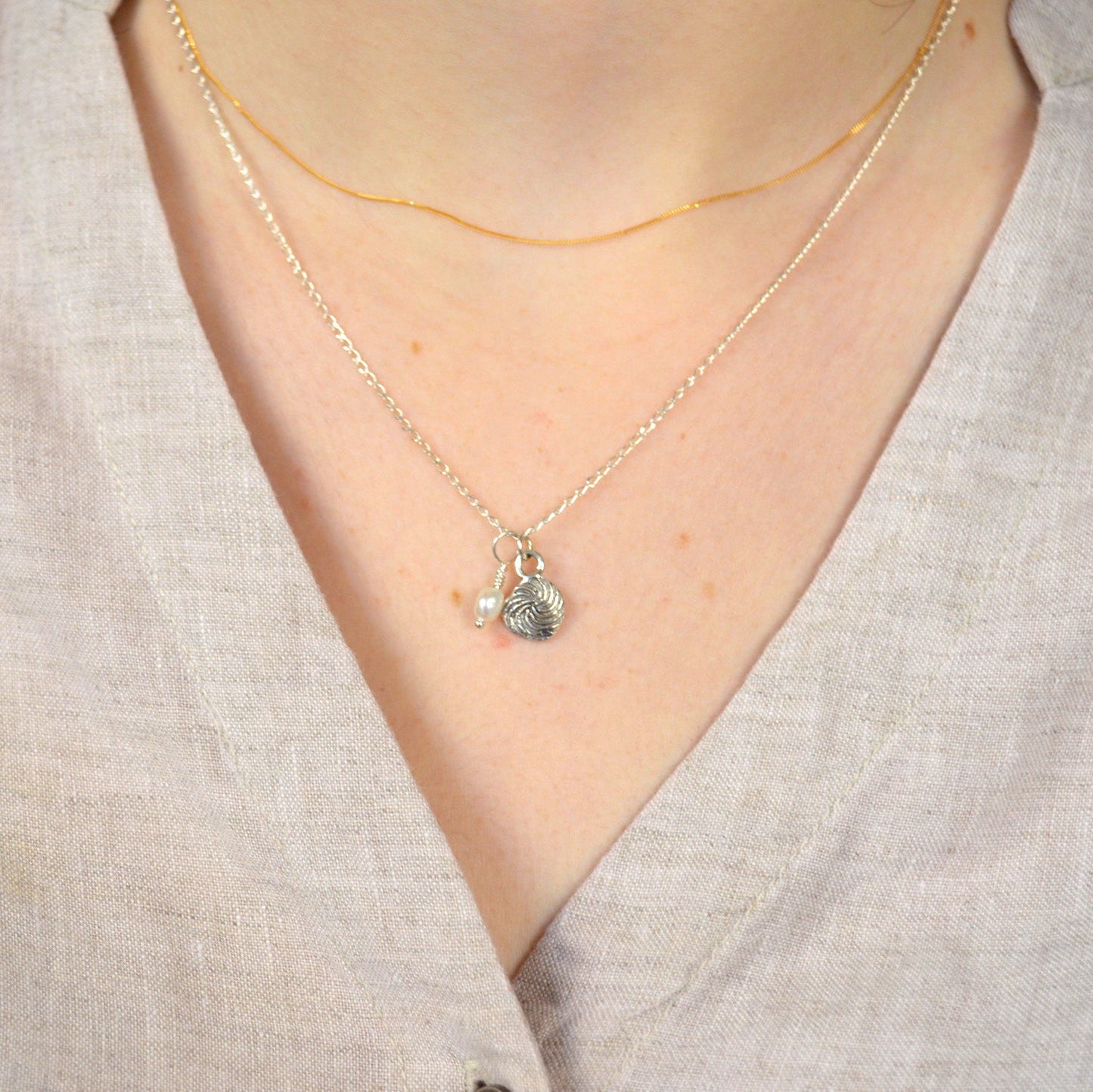 Necklace with a small pendant worn by a person in a light-colored shirt