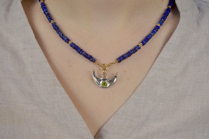 Necklace with blue beads and a silver pendant on a neutral background
