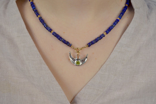 Necklace with blue beads and a silver pendant on a neutral background