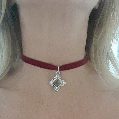 Red choker necklace with a silver pendant on a person's neck